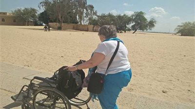 سائحة إنجليزية تزور آثار تونا الجبل على كرسي متحرك