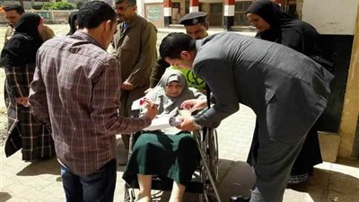 رئيس لجنة بطنطا يتوجه لسيدة مسنة لمساعدتها في الإدلاء بصوتها