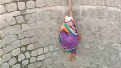 شاهد.. امرأة تخاطر بحياتها تسلقت جدار بئر للحصول على الماء