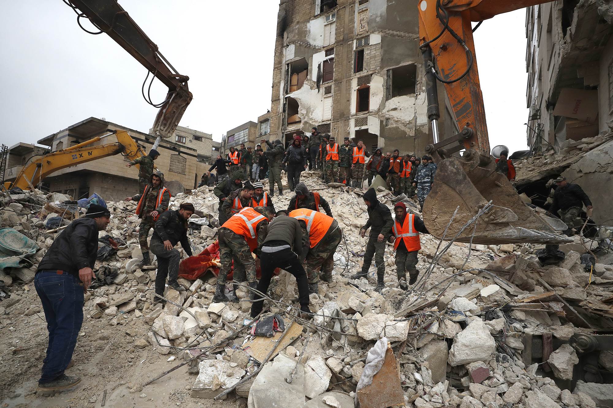    عناصر الدفاع المدني وقوات الأمن يبحثون وسط حطام المباني المنهارة في مدينة حماة السورية